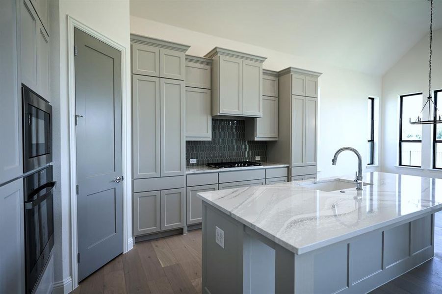 Kitchen with decorative backsplash, gas stovetop and walk-in pantry