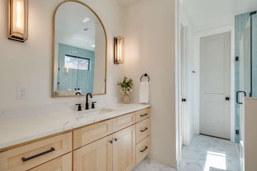 Full bath with vanity, light marble finish floors, and a shower stall