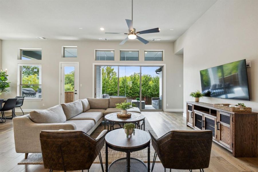 Living room with light wood-type flooring, a towering ceiling, and ceiling fan