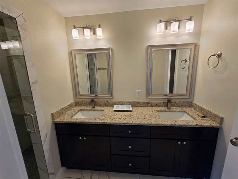 Full bath featuring a shower stall and double vanity