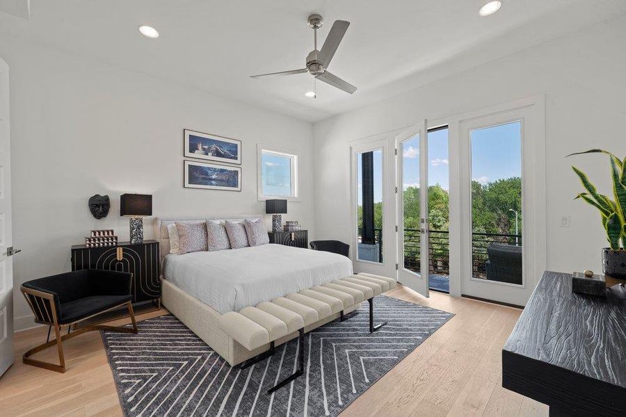 Spacious primary suite featuring wide-plank flooring, oversized windows,  and a peaceful private balcony.