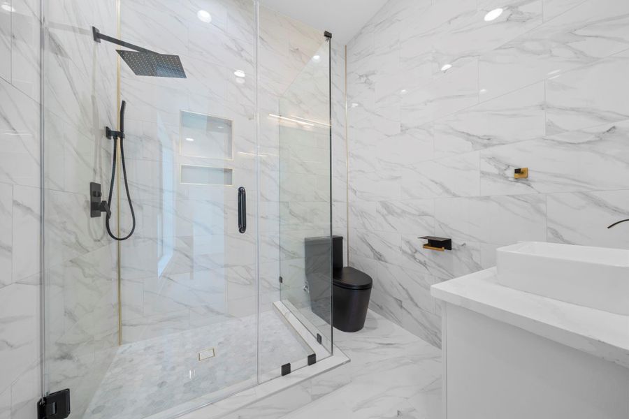 This bedroom is complete with this charming en-suite bath, featuring a glass enclosed shower and marble tiles. This bedroom is complete with this charming en-suite bath, featuring a glass enclosed shower and marble tiles.
