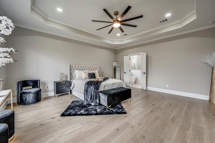 Bedroom featuring a raised ceiling and light wood-type flooring