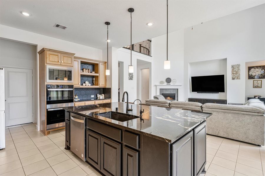 Gorgeous kitchen comes equipped with stainless steel appliances, beautiful natural wood cabinetry, granite countertops, a large eat-in island, 100 percent sink with drinking water and soap fixtures, a great sized pantry tucked behind the stove, and a pot filler over the stove for convenience.