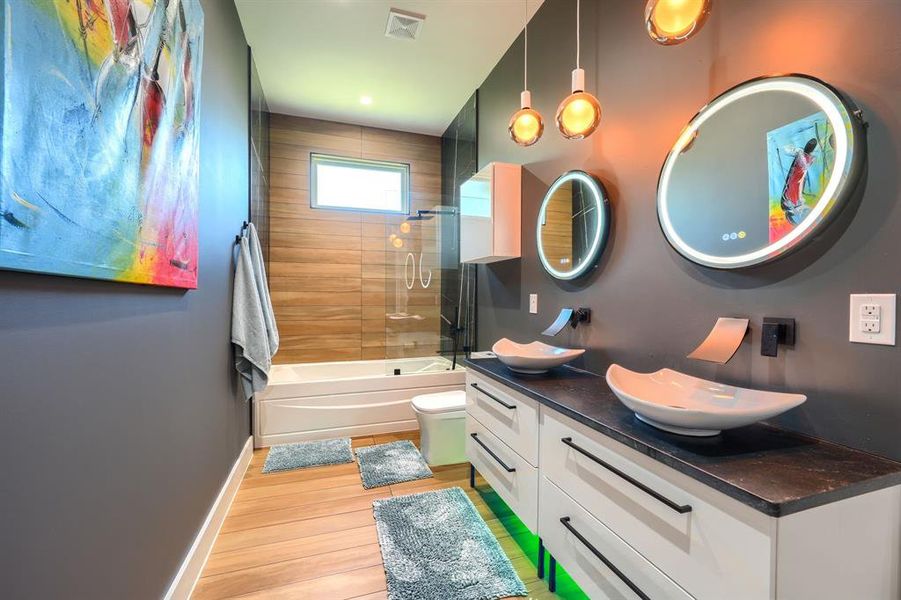 Bathroom featuring bath / shower combo with glass door and light wood-style floors Bathroom featuring bath / shower combo with glass door and light wood-style floors
