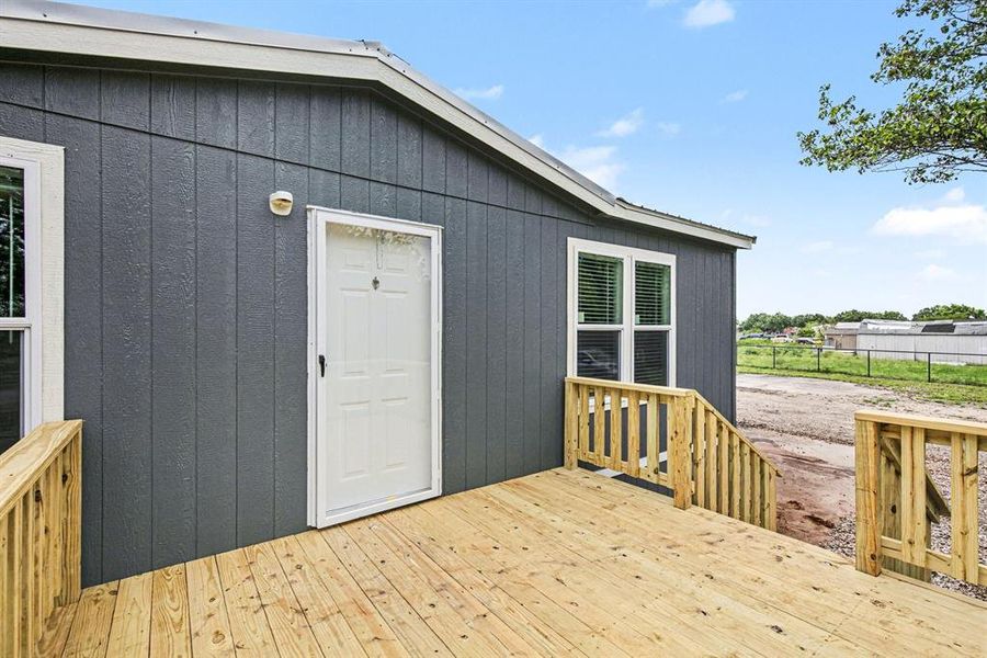 Enjoy private sunset views on this exterior entry featuring a newly constructed wood deck, wood railing, and a white storm door.  Bring your chairs and watch the Texas Sunsets!