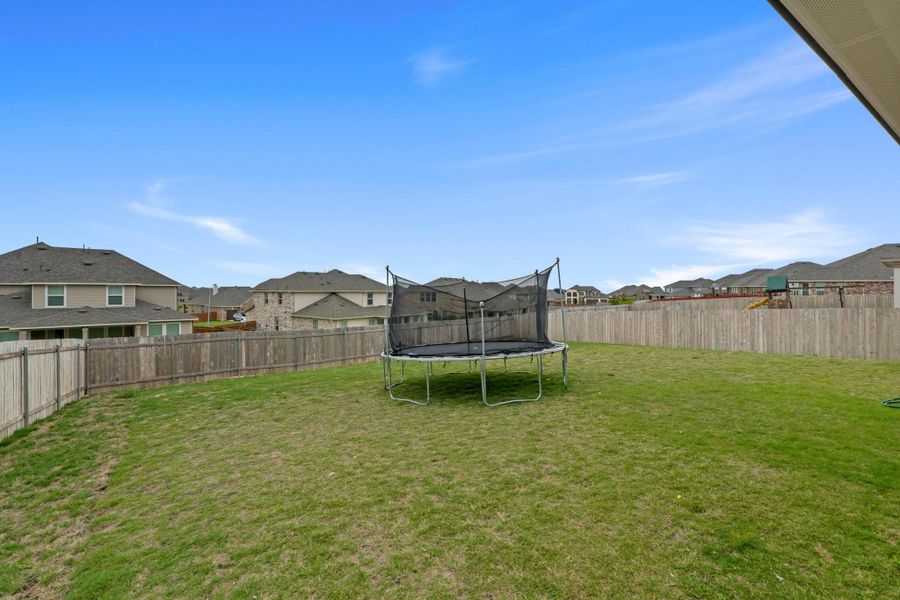 Spacious backyard featuring an expansive lawn and full privacy fencing