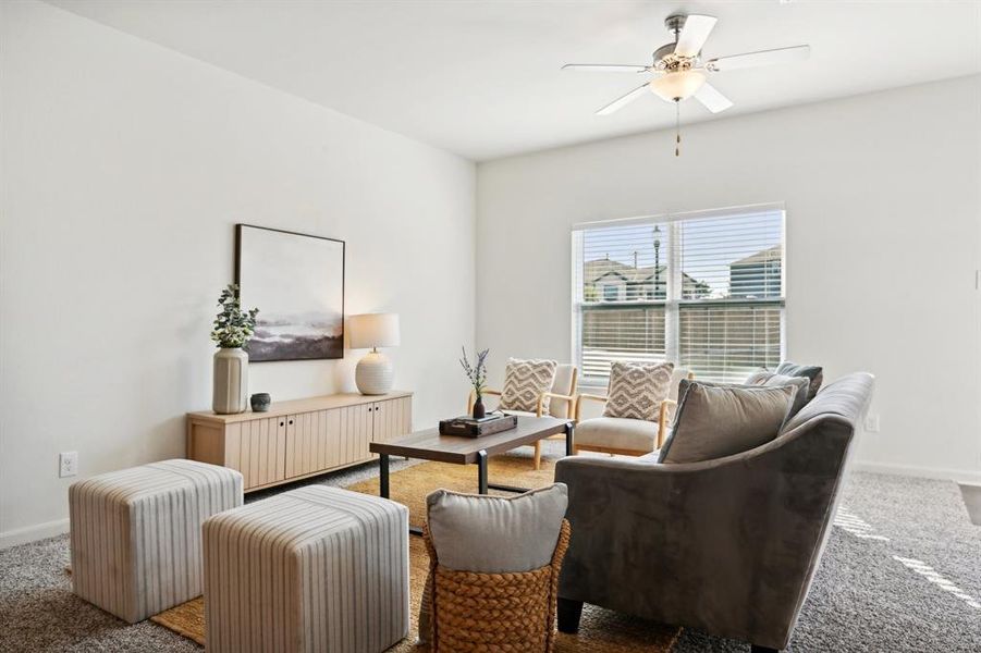 Carpeted living room featuring ceiling fan