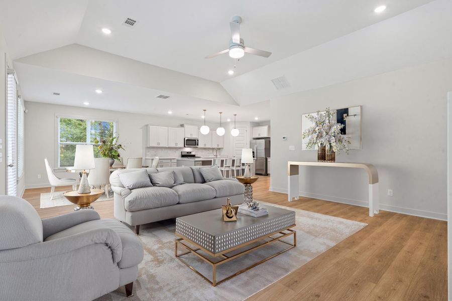 Open-concept living area featuring vaulted ceilings with recessed lighting, wood-finish flooring, and a modern ceiling fan Open-concept living area featuring vaulted ceilings with recessed lighting, wood-finish flooring, and a modern ceiling fan