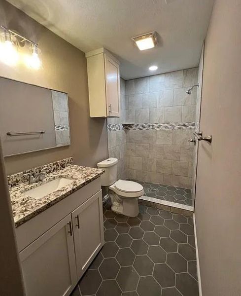 Bathroom featuring vanity, a stall shower, dark tile patterned floors, and a textured ceiling