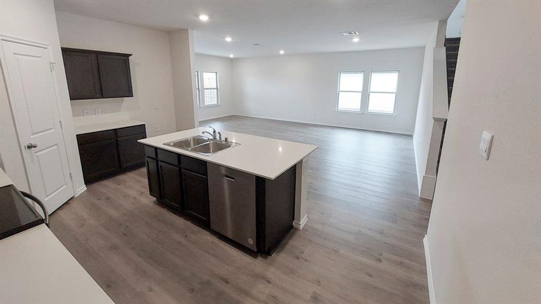 Kitchen featuring light countertops, wood finished floors, an island with sink, dishwasher, and recessed lighting Kitchen featuring light countertops, wood finished floors, an island with sink, dishwasher, and recessed lighting