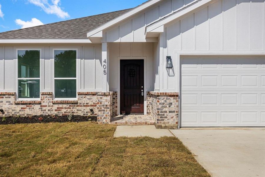 View of exterior entry featuring a yard and a garage