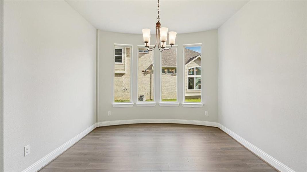 Unfurnished dining area featuring wood finished floors and a chandelier Unfurnished dining area featuring wood finished floors and a chandelier
