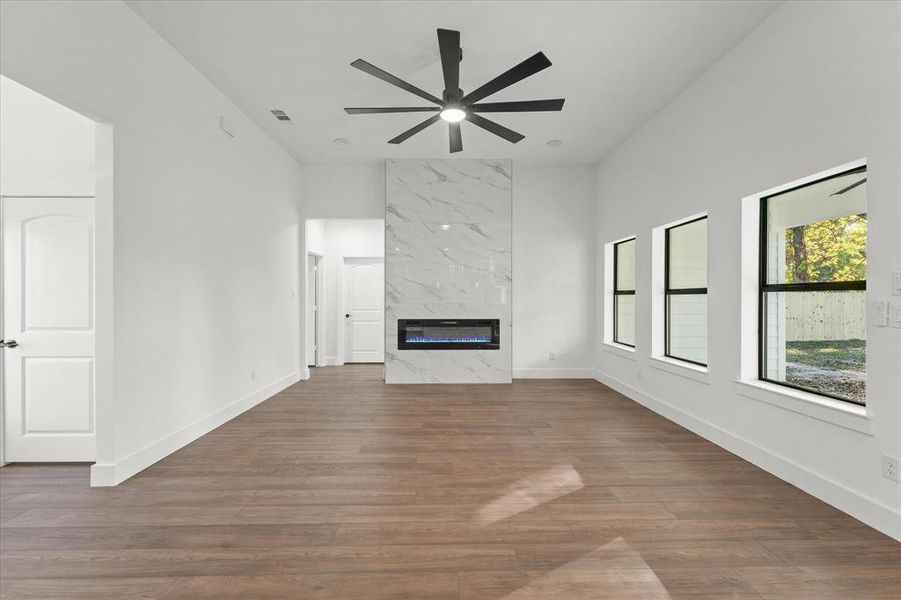 Unfurnished living room featuring ceiling fan, dark wood-type flooring, and a premium fireplace