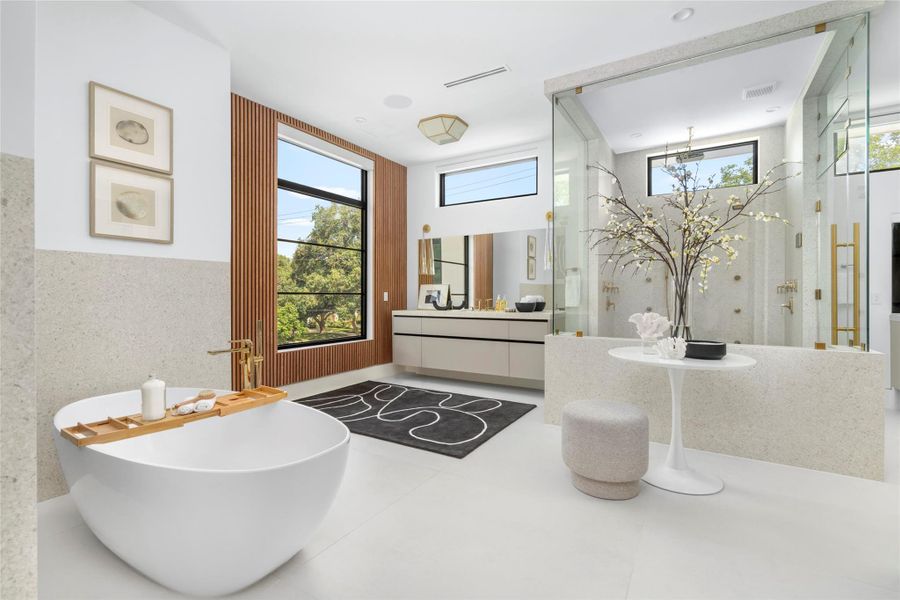 [Primary Bath] The lavishly-appointed primary bath features porcelain surfaces; Circa lighting; fluted wood paneling; soaking tub, and shower area with two wall and one hand-held shower heads and steam system.
