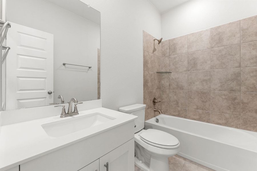 Bathroom with toilet, vanity, washtub / shower combination, and tile patterned flooring Bathroom with toilet, vanity, washtub / shower combination, and tile patterned flooring