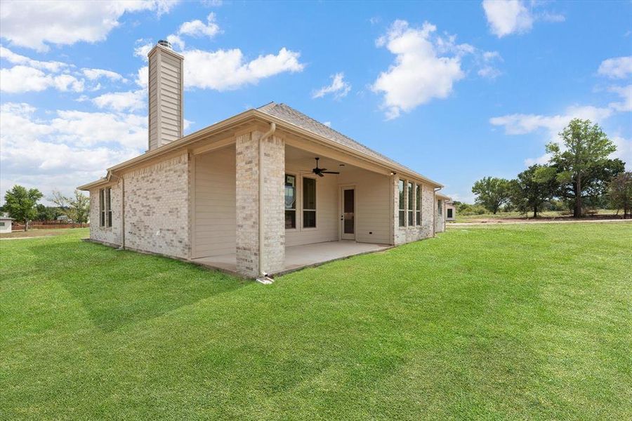 Rear view of house featuring a lawn, ceiling fan, and a patio