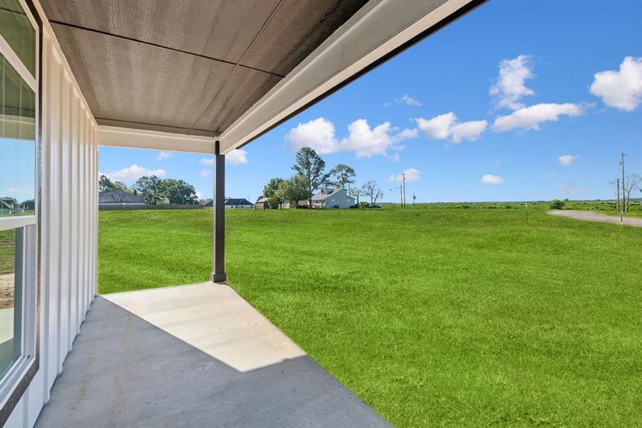 View of grassy yard featuring a patio area View of grassy yard featuring a patio area