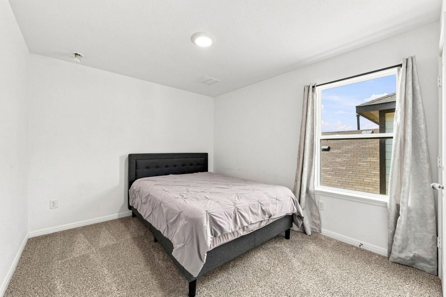 Natural light pours through a large window illuminating neutral walls and plush carpeting.