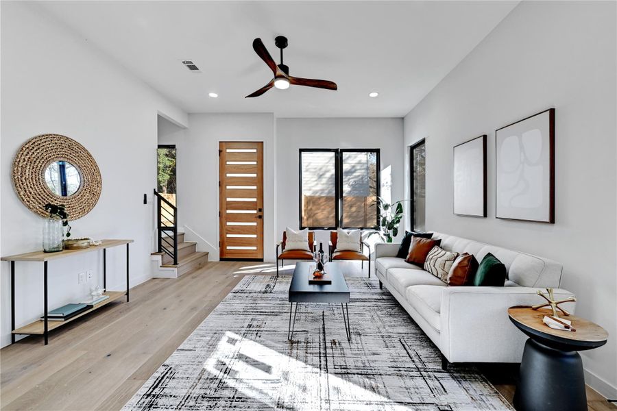 Living room featuring visible vents, baseboards, stairway, recessed lighting, and light wood-style flooring