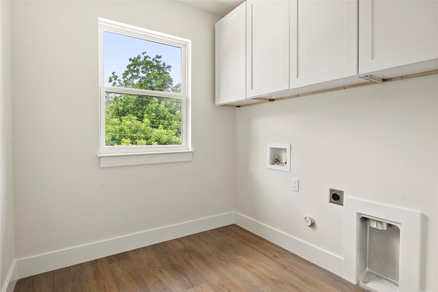 Ample cabinetry and wood flooring make this dedicated laundry area a highly functional space.