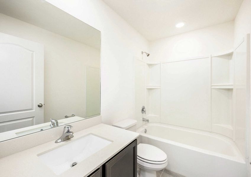 Caladesi floor plan's bathroom with quartzÂ countertops and a bathtub/shower with a light above the shower.