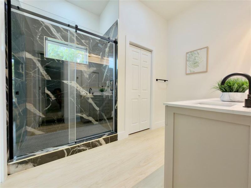 Full bathroom featuring vanity, light wood-style floors, a marble finish shower, and a closet