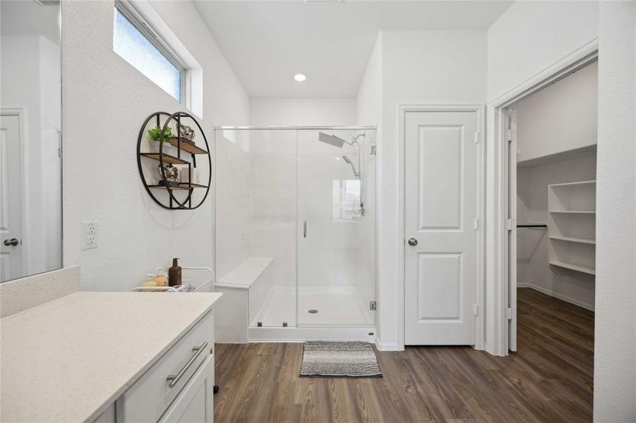 Primary bathroom with granite counter tops, oversized shower with sitting bench, and large walk in closet