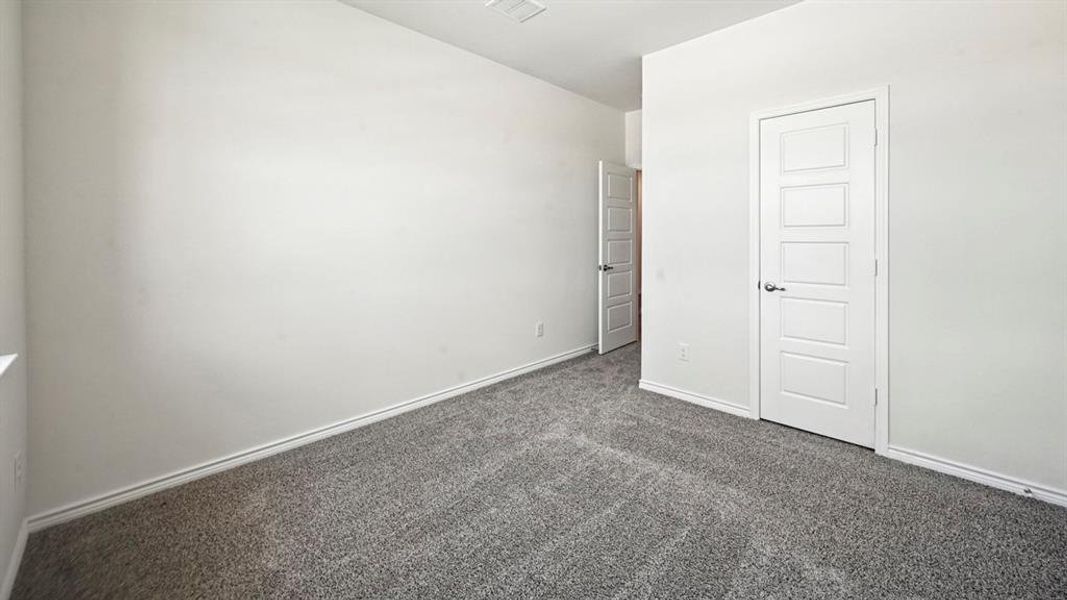 Spacious room featuring neutral carpeting, white baseboards, and two contemporary five-panel interior doors with brushed nickel hardware