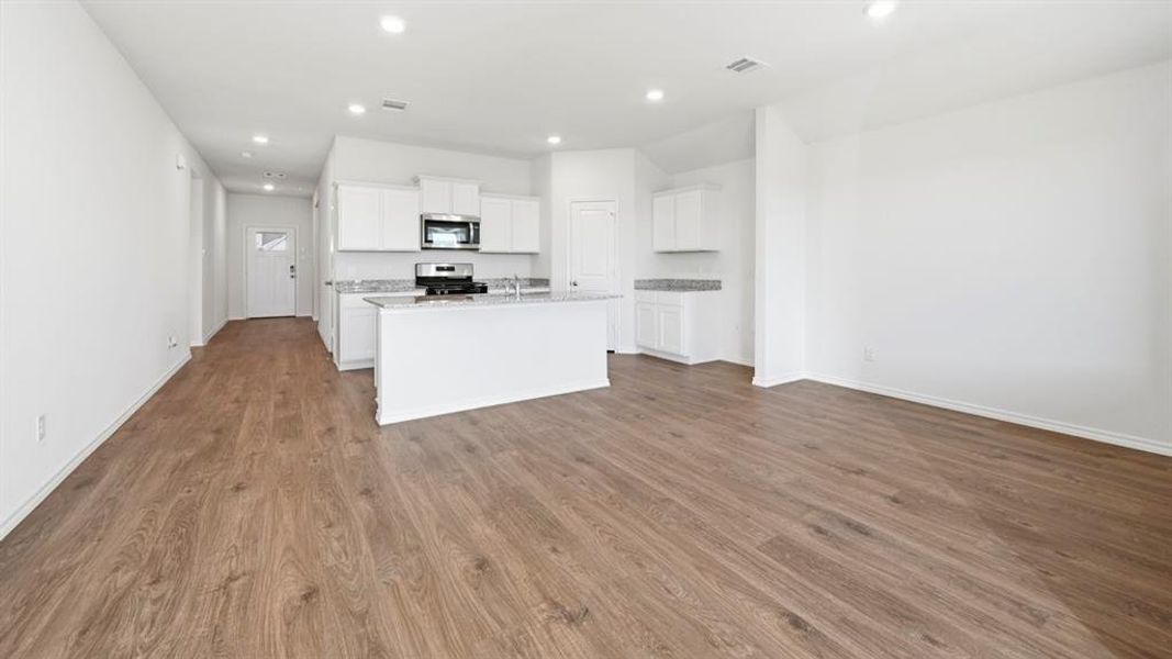 Kitchen featuring white cabinets, appliances with stainless steel finishes, recessed lighting, an island with sink, and dark wood-type flooring