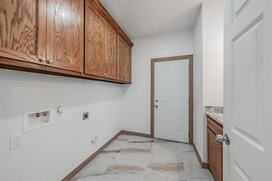 Clothes washing area with hookup for a gas dryer, washer hookup, baseboards, cabinet space, and electric dryer hookup