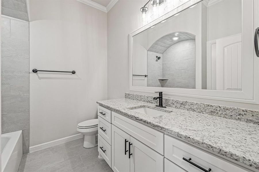 Bathroom with vanity, crown molding, and light tile patterned flooring