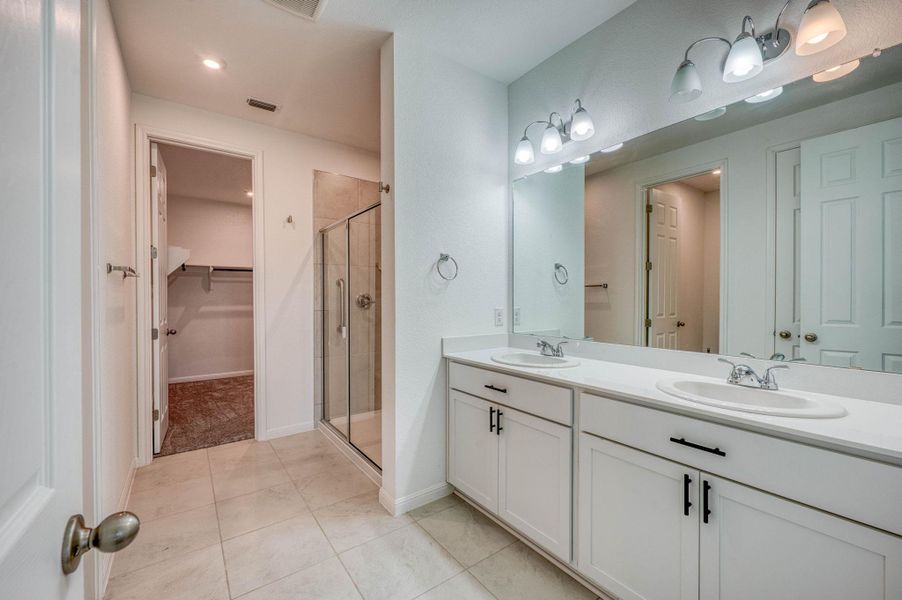 An integrated vanity area features a double sink design alongside a walk-in shower.