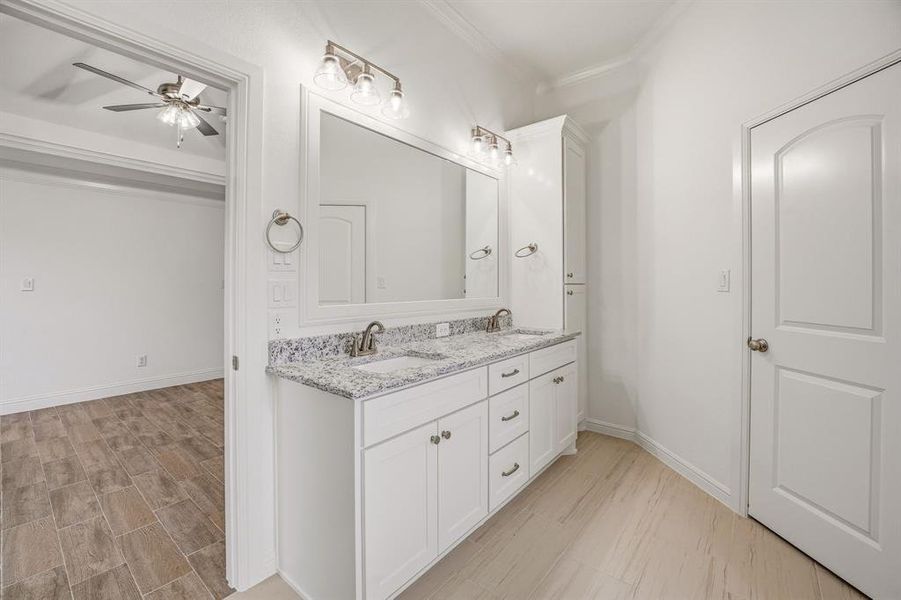 The bathroom features a double vanity with a speckled countertop, a large mirror, and overhead lighting