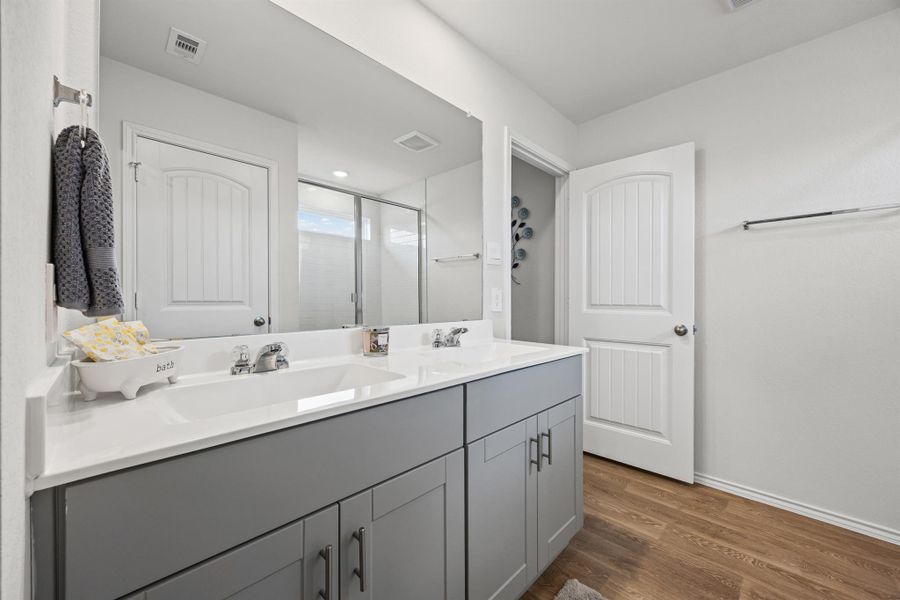 Full bathroom with double vanity, dark wood-type flooring, and a stall shower