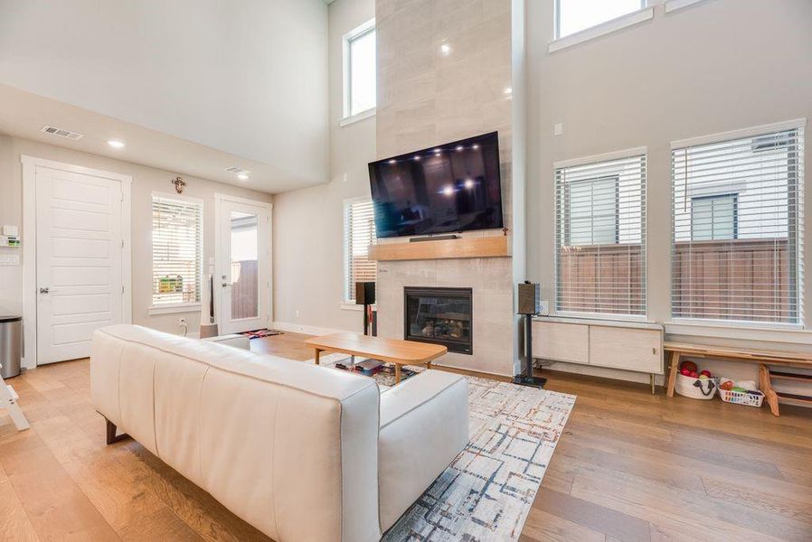Living area featuring a high ceiling, light wood-style floors, and a tile fireplace