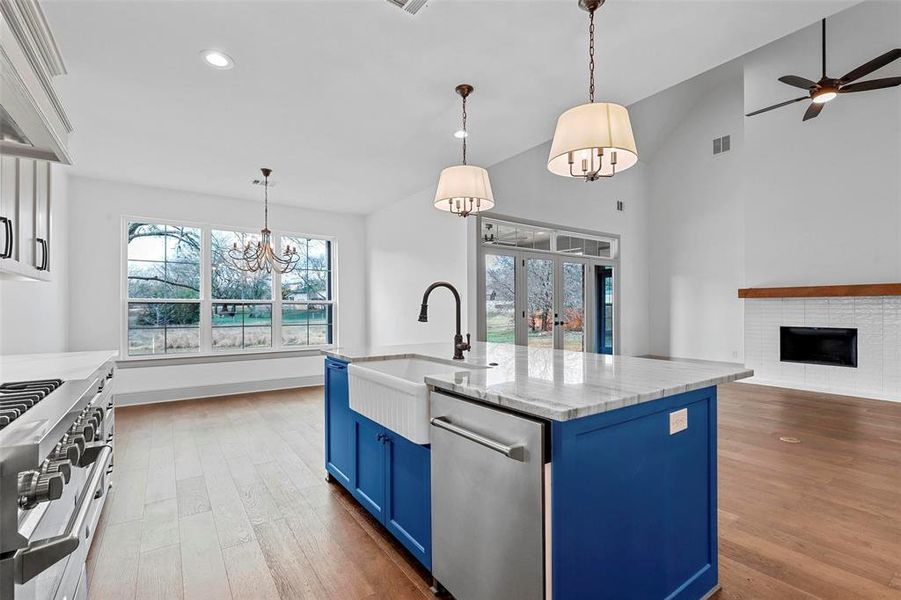 Kitchen with sink, hanging light fixtures, an island with sink, blue cabinets, and french doors