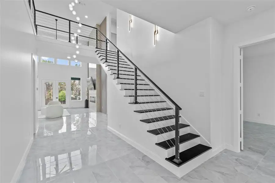 Contemporary staircase featuring black treads, white risers, and a cable railing system
