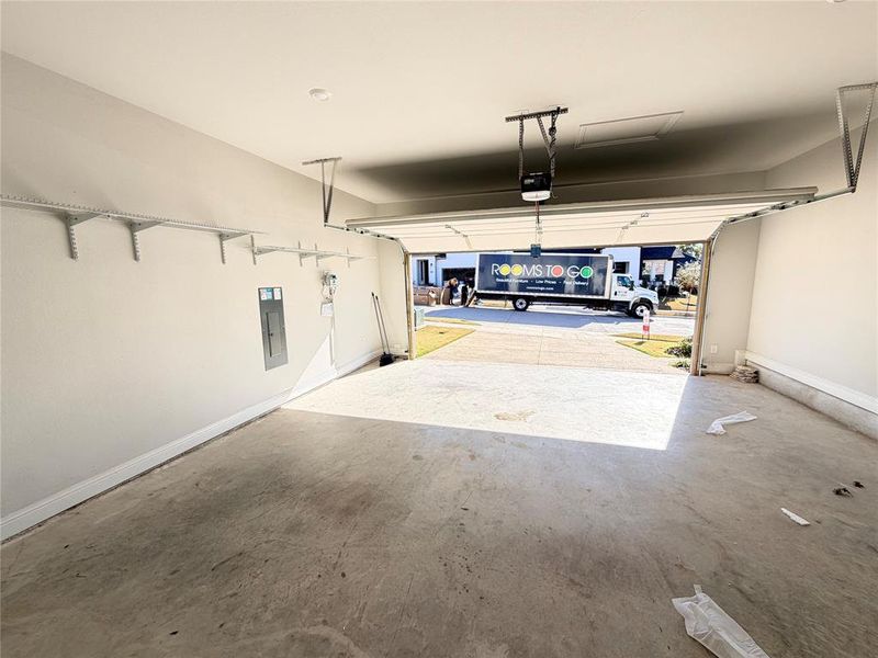 Garage featuring electric panel and a garage door opener Garage featuring electric panel and a garage door opener
