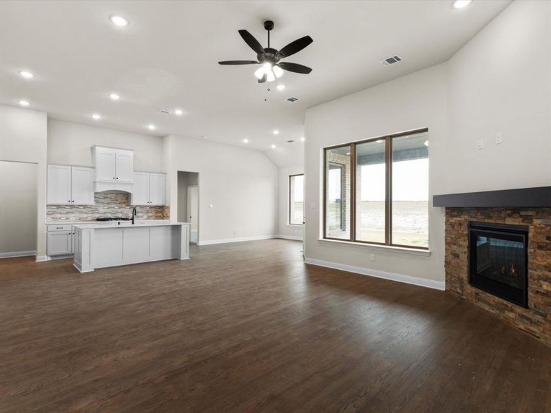 Unfurnished living room featuring recessed lighting, a stone fireplace, dark wood-style floors, a ceiling fan, and vaulted ceiling