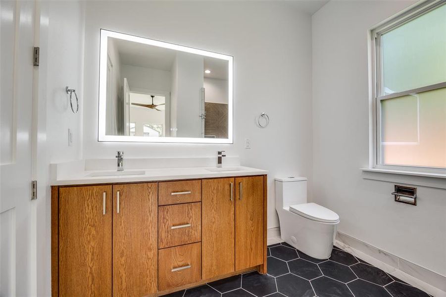 Full bathroom with double vanity, dark tile patterned floors, and ceiling fan Full bathroom with double vanity, dark tile patterned floors, and ceiling fan