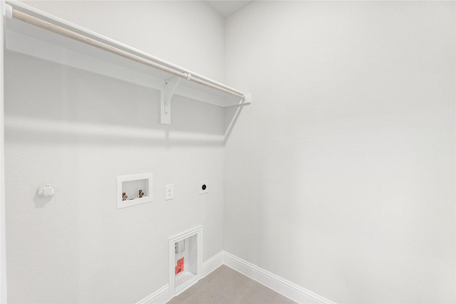Empty laundry room with upper shelf, hanging rod, washer hookups, and dryer vent connection on white walls