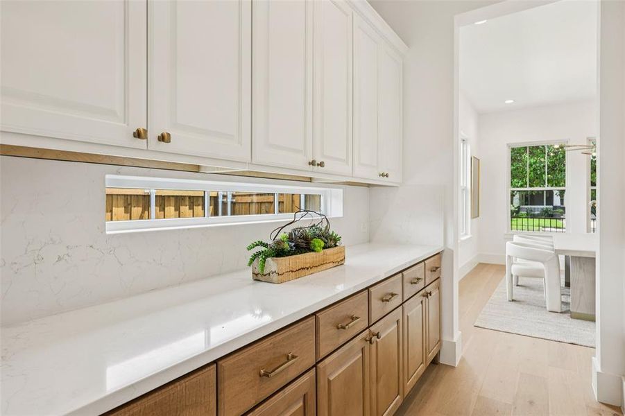 Custom built-in cabinetry featuring white upper cabinets and wood-finish lower cabinets, accented with brass hardware