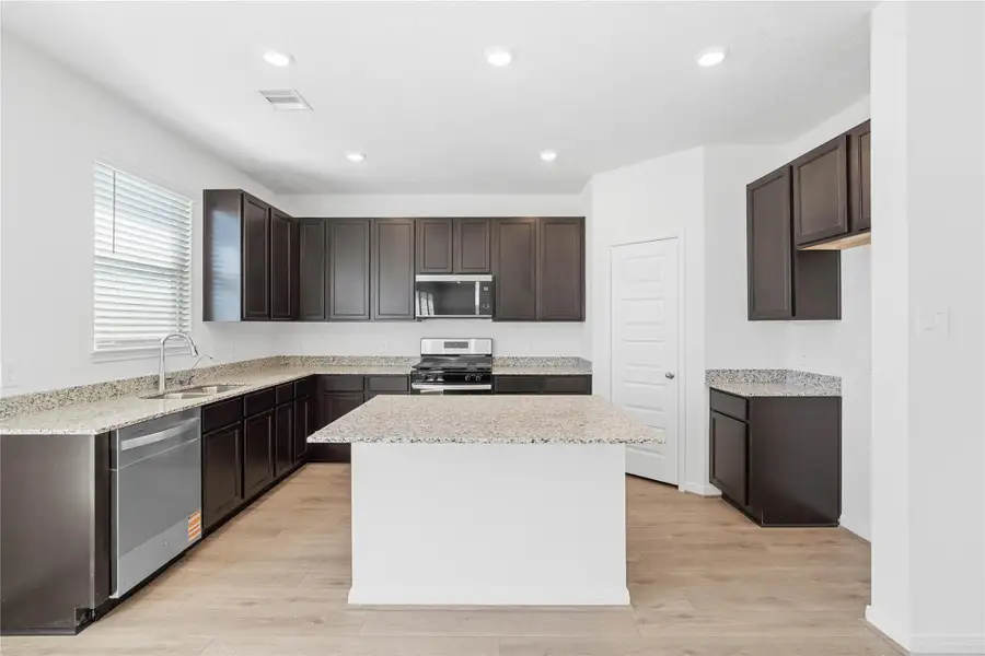 The kitchen island serves as a natural gathering point in this open-concept main living space. The island offers an added breakfast bar as well as a large surface area for a party spread.