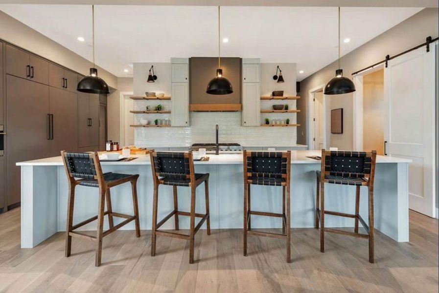 Kitchen featuring a kitchen bar, a barn door, light wood finished floors, and pendant lighting