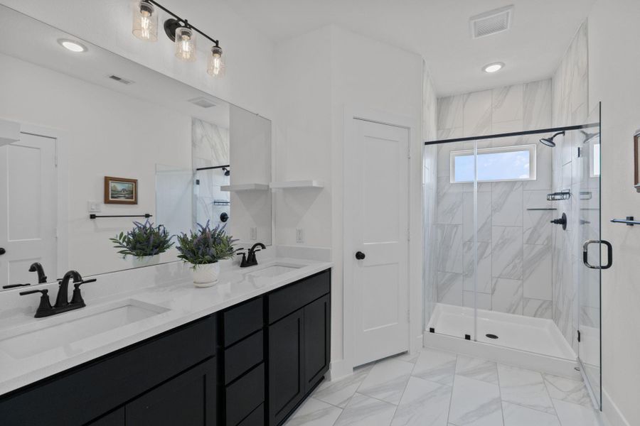 Beautiful primary bathroom has two separate sinks, walk in shower and tile floor.
