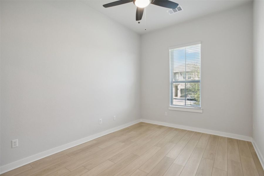 Unfurnished room featuring light wood-style flooring, visible vents, ceiling fan, and baseboards