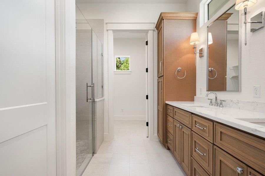 Bathroom featuring a double vanity with stone countertops, wood cabinetry, and a glass-enclosed shower