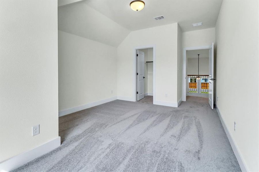 Carpeted room featuring a neutral color palette, sloped ceiling, and white trim Carpeted room featuring a neutral color palette, sloped ceiling, and white trim