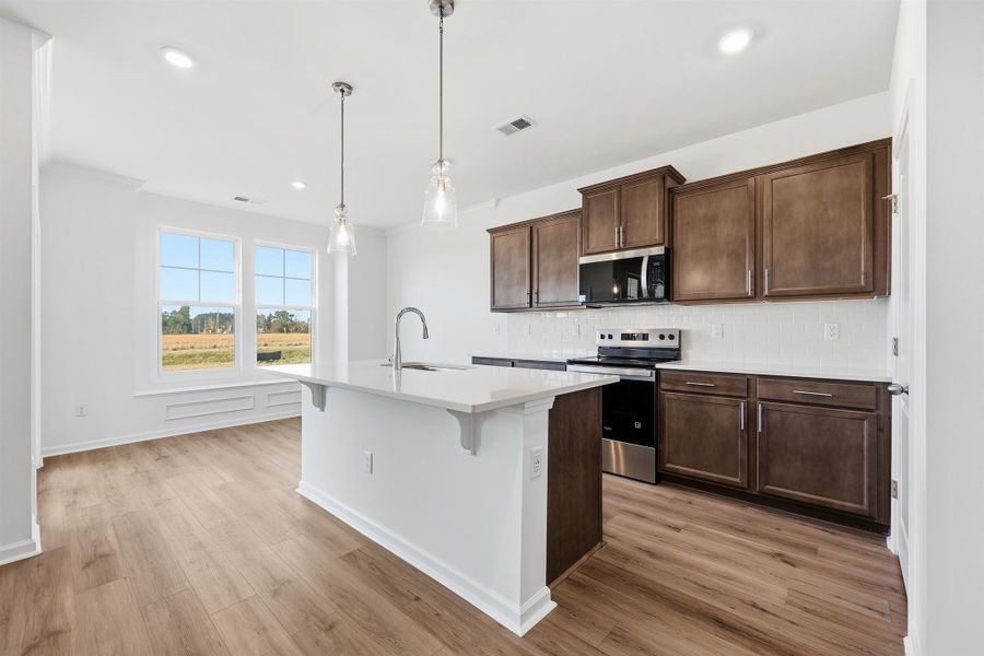 Kitchen with stainless steel appliances, tasteful backsplash, a kitchen island with sink, a kitchen breakfast bar, and hanging light fixtures
